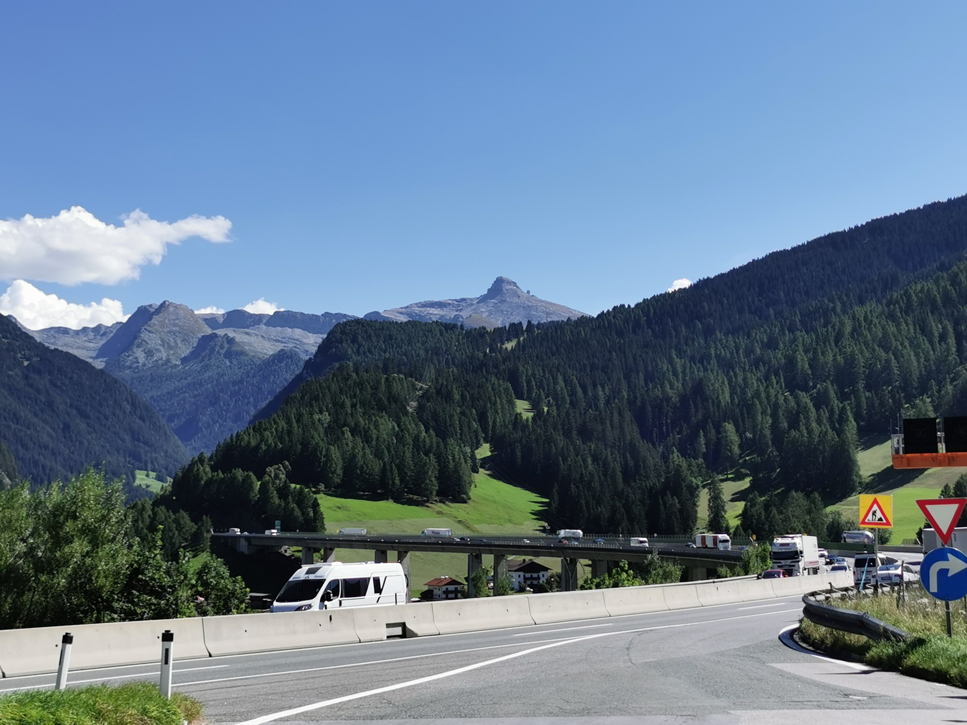 Brenner A13 motorway with trucks, mountain valley and signed junction