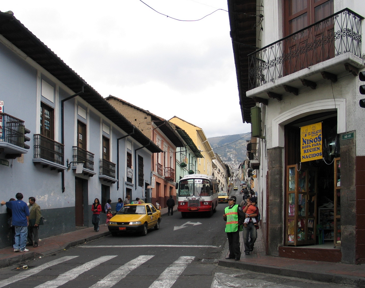 Urban street in Quito's historic centre with buses, pedestrians and dense buildings