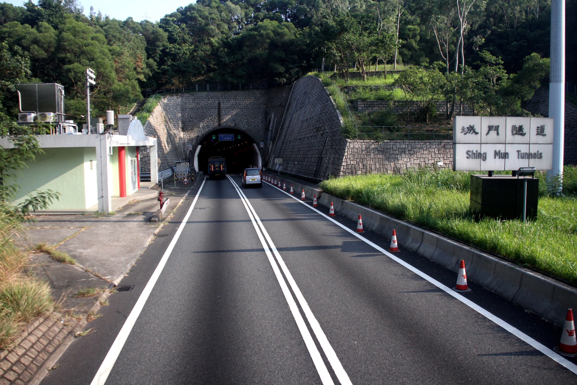 Shing Mun Tunnels approach with bilingual signs and traffic cones