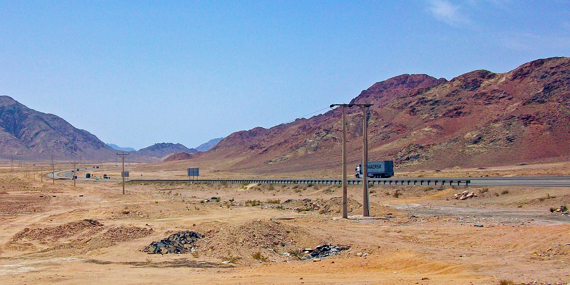 Jordan's Desert Highway near the Wadi Rum turnoff, with trucks crossing a dry mountain valley