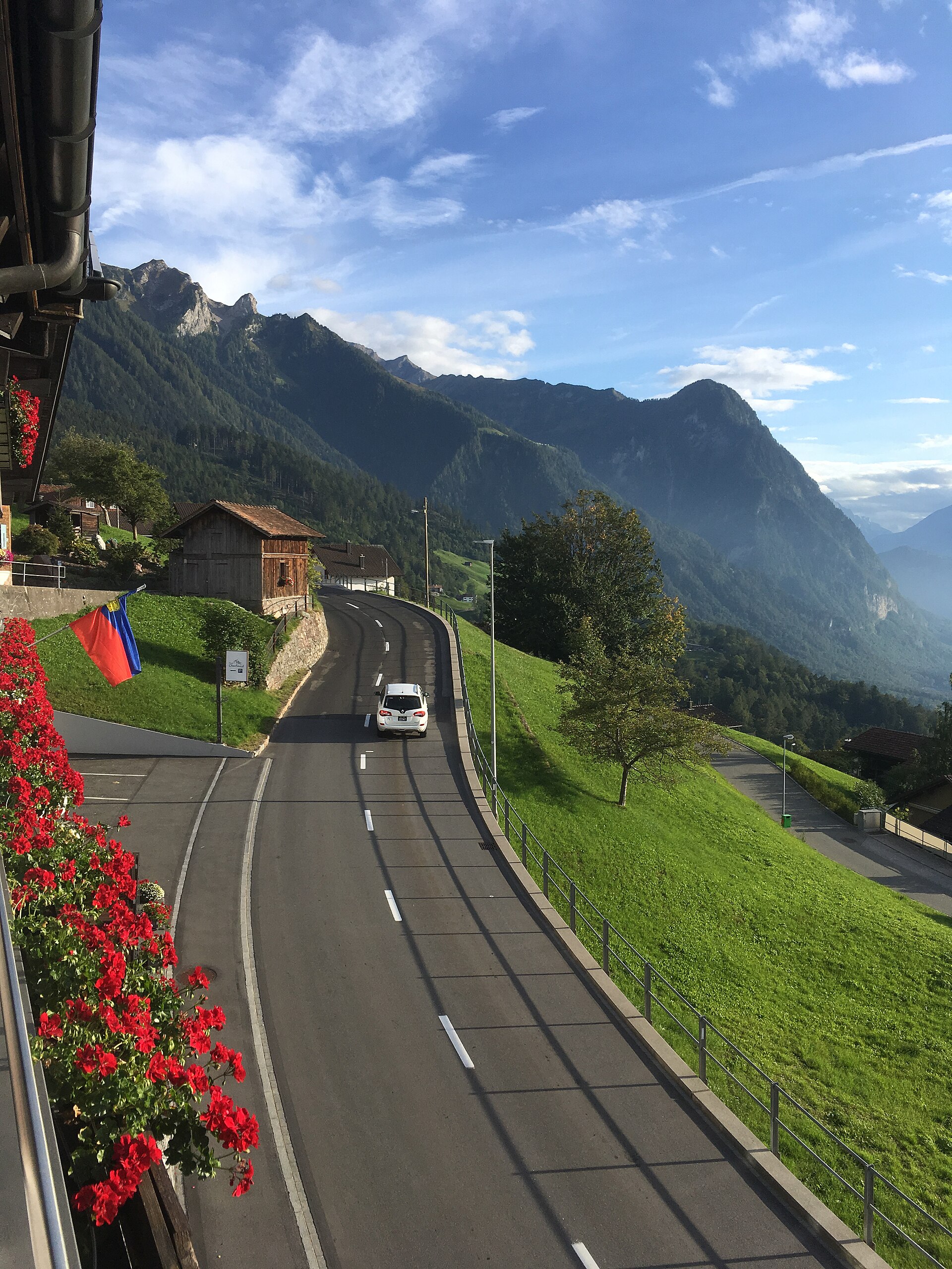 A winding road through Triesenberg with a mountain ridge beyond