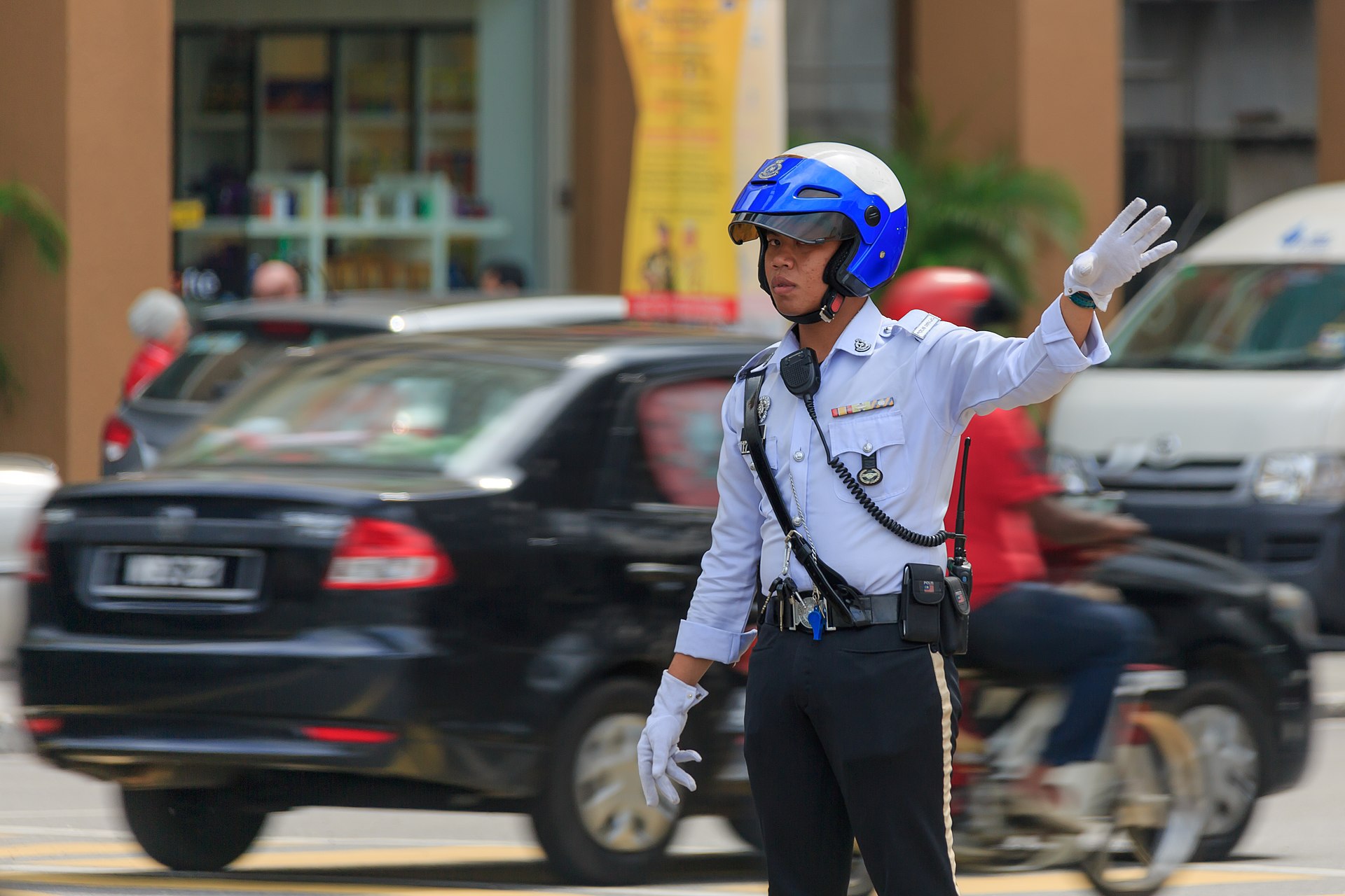 Traffic police officer directing cars and motorcycles at a Kuala Lumpur junction