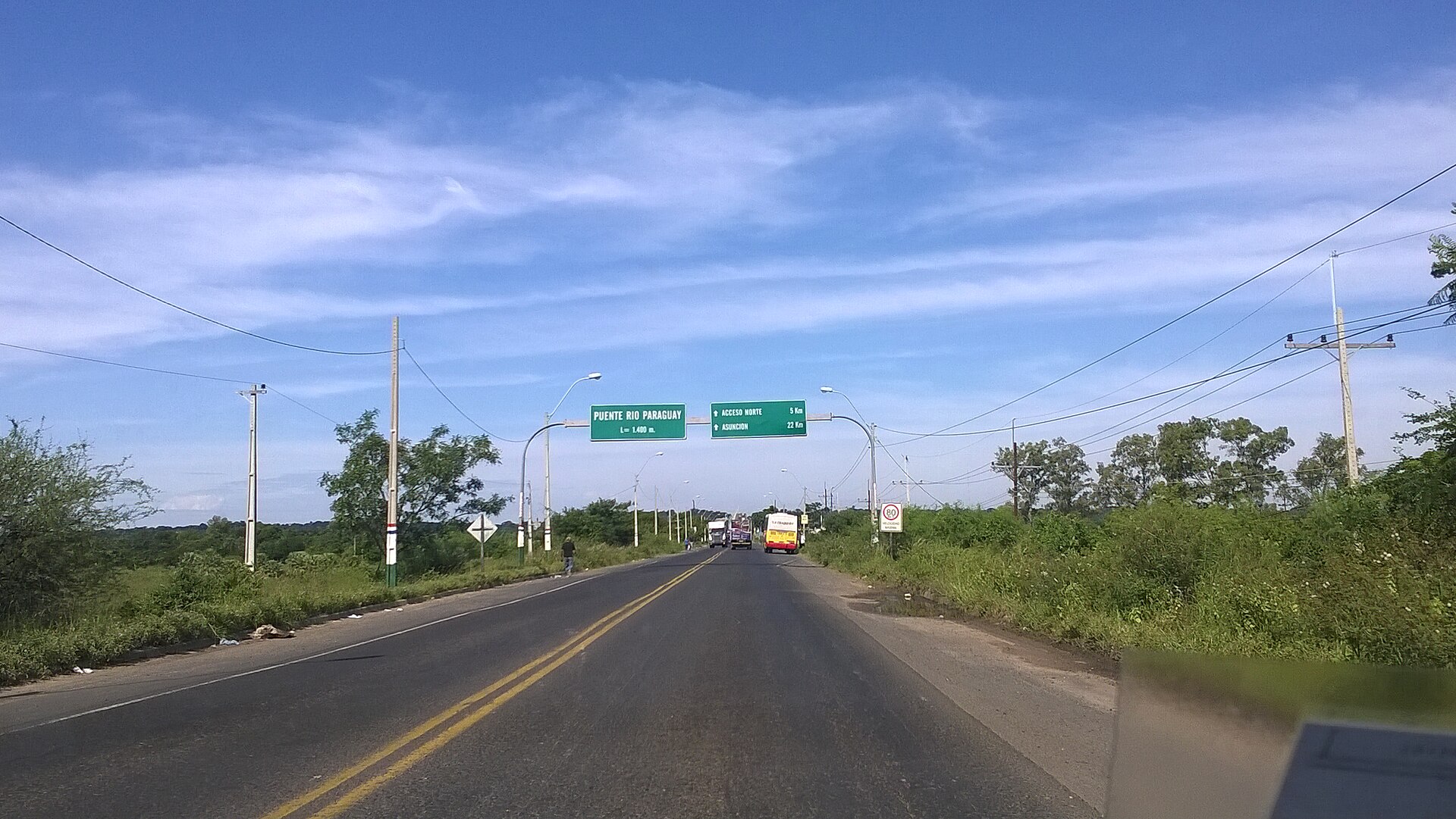 Road signs and traffic at the Remanso bridge approach on PY09 near Asunción