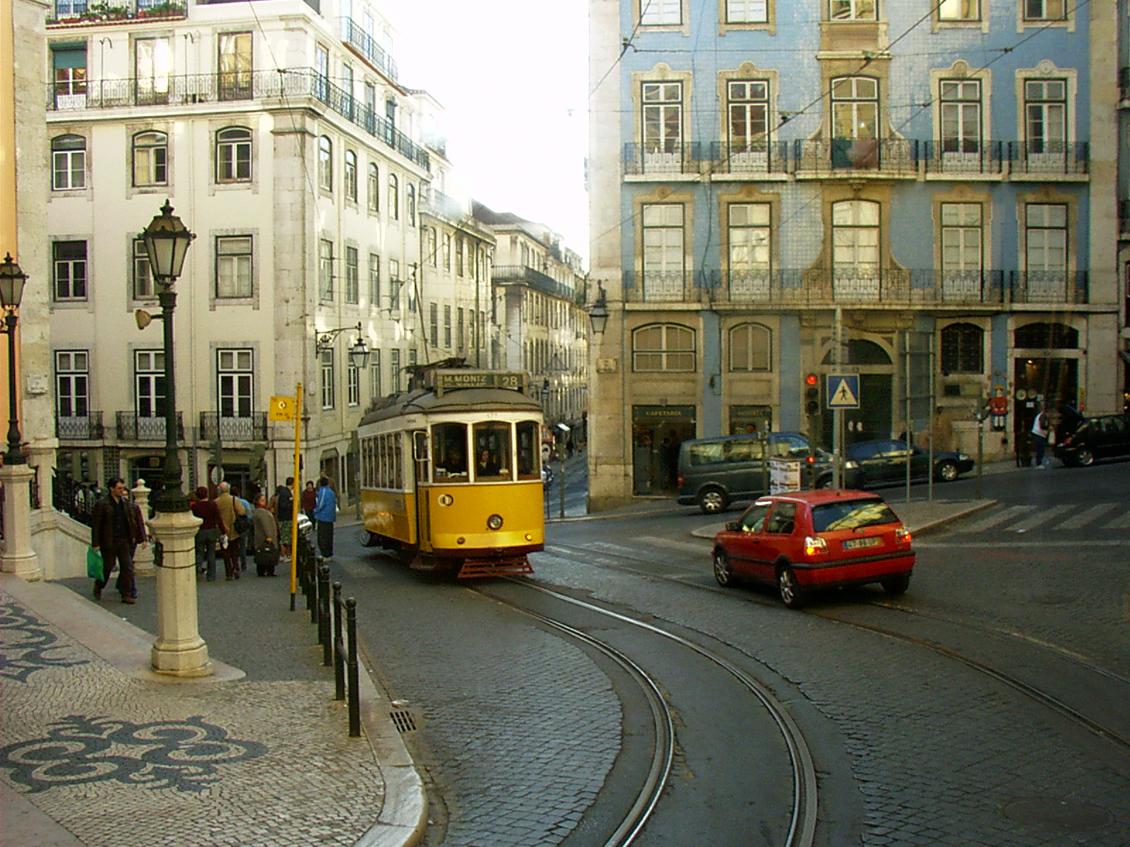 Yellow tram climbing a narrow street in Lisbon
