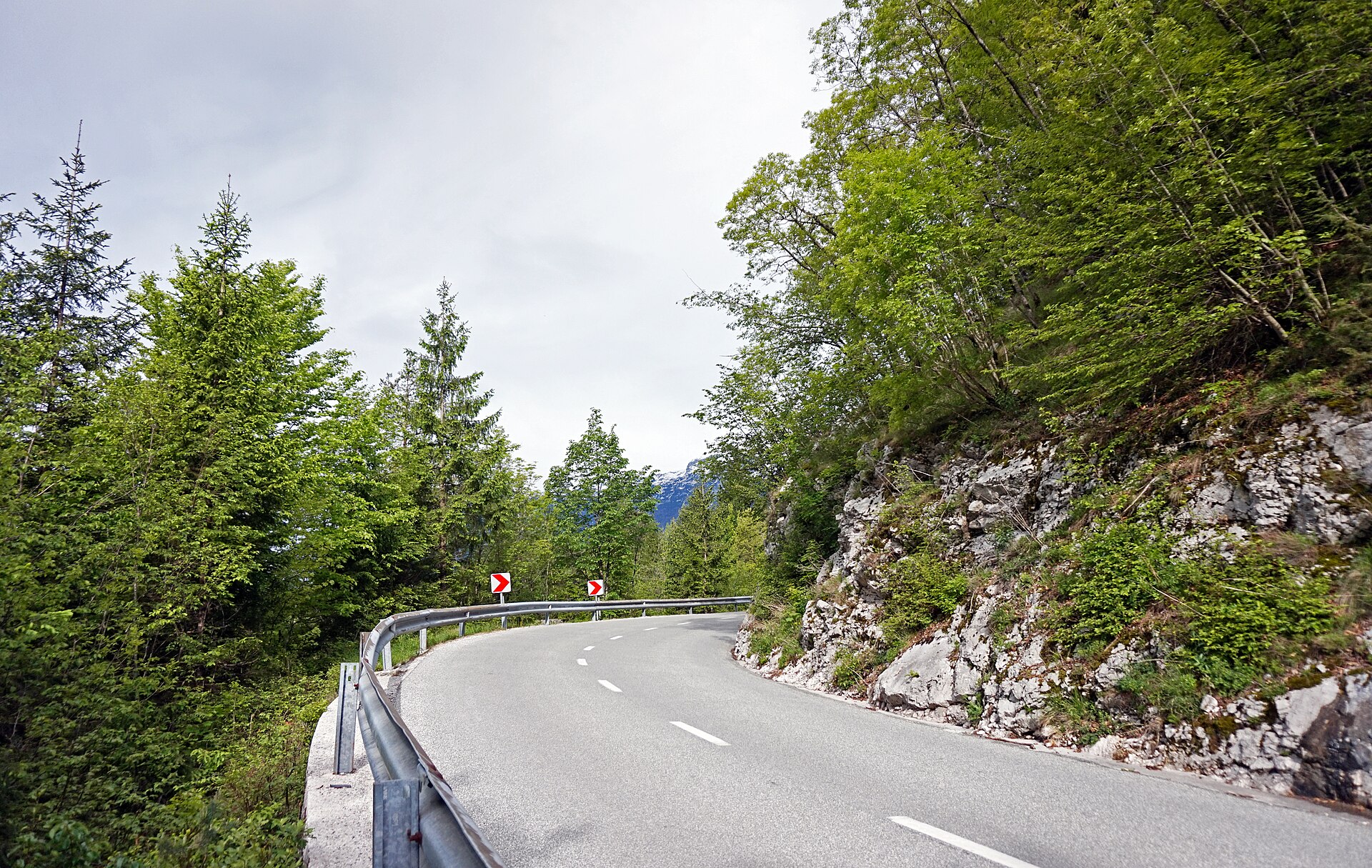 Road 206 curves beside a rocky slope in the Soča region of Slovenia