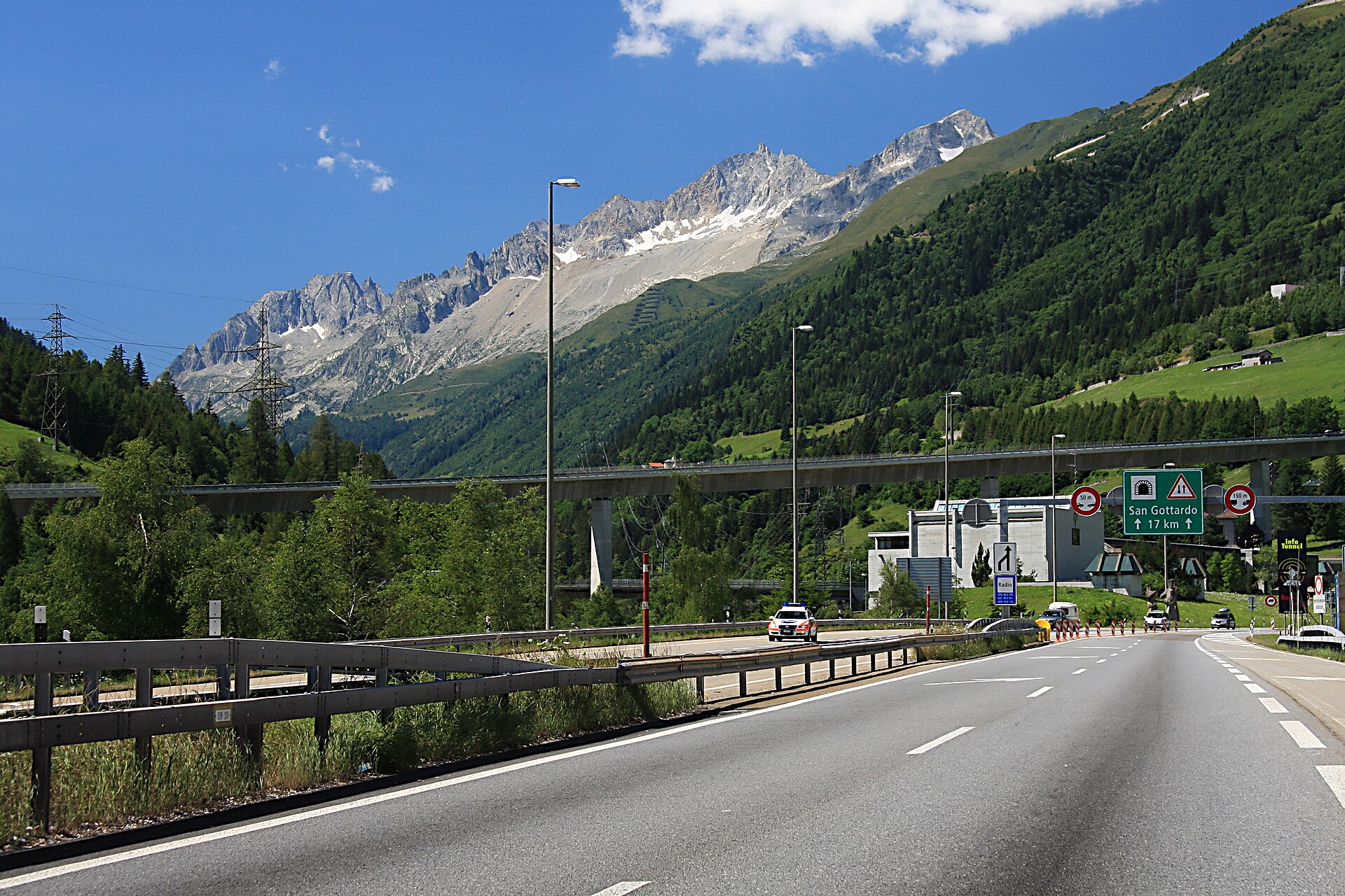 Approach road to the Gotthard tunnel with a San Gottardo sign and Alpine mountains