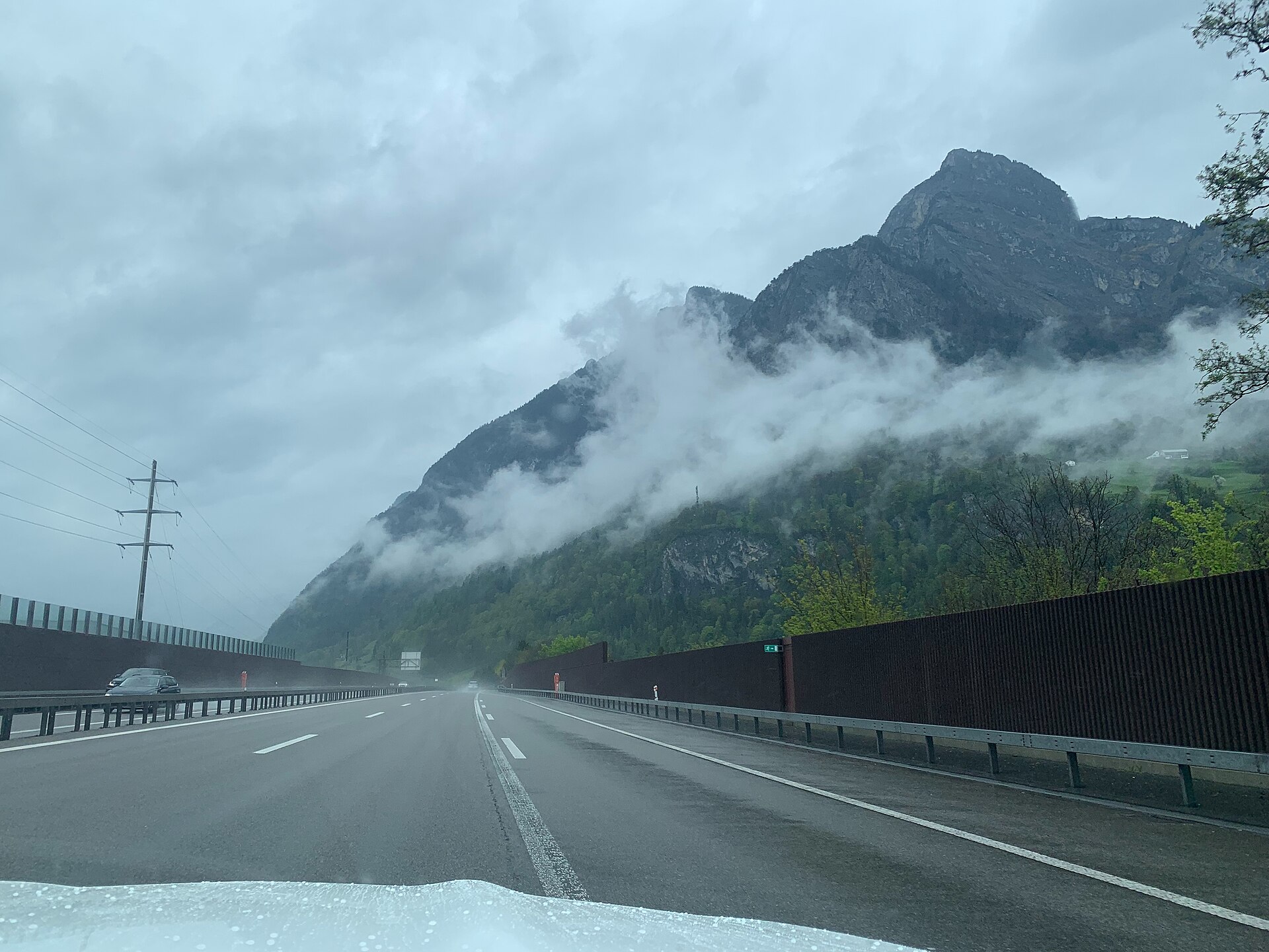 Swiss motorway in the Alps during rain with a tunnel exit ahead