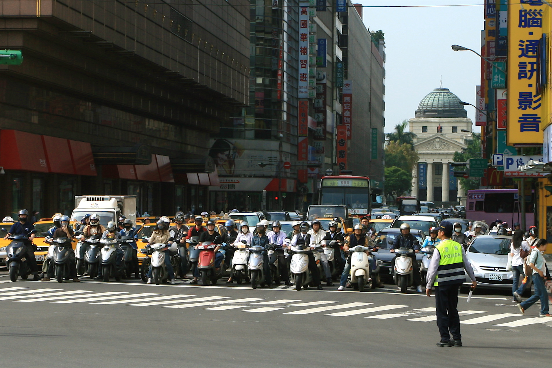 Scooters waiting beside cars at a Taipei junction